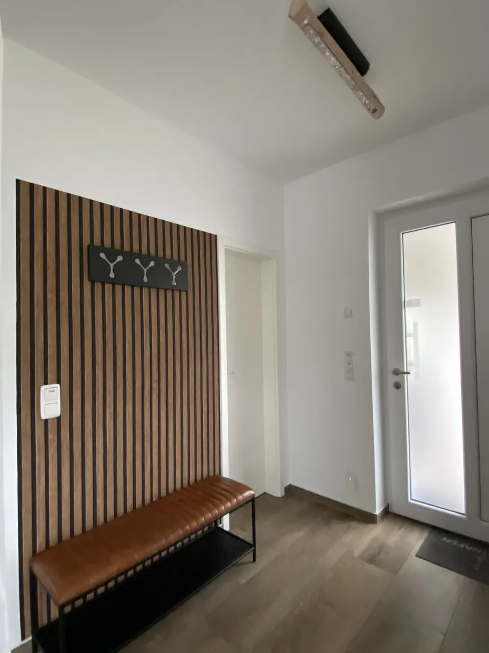 Garderobe mit Holzpaneelen und Sitzbank im Eingangsbereich