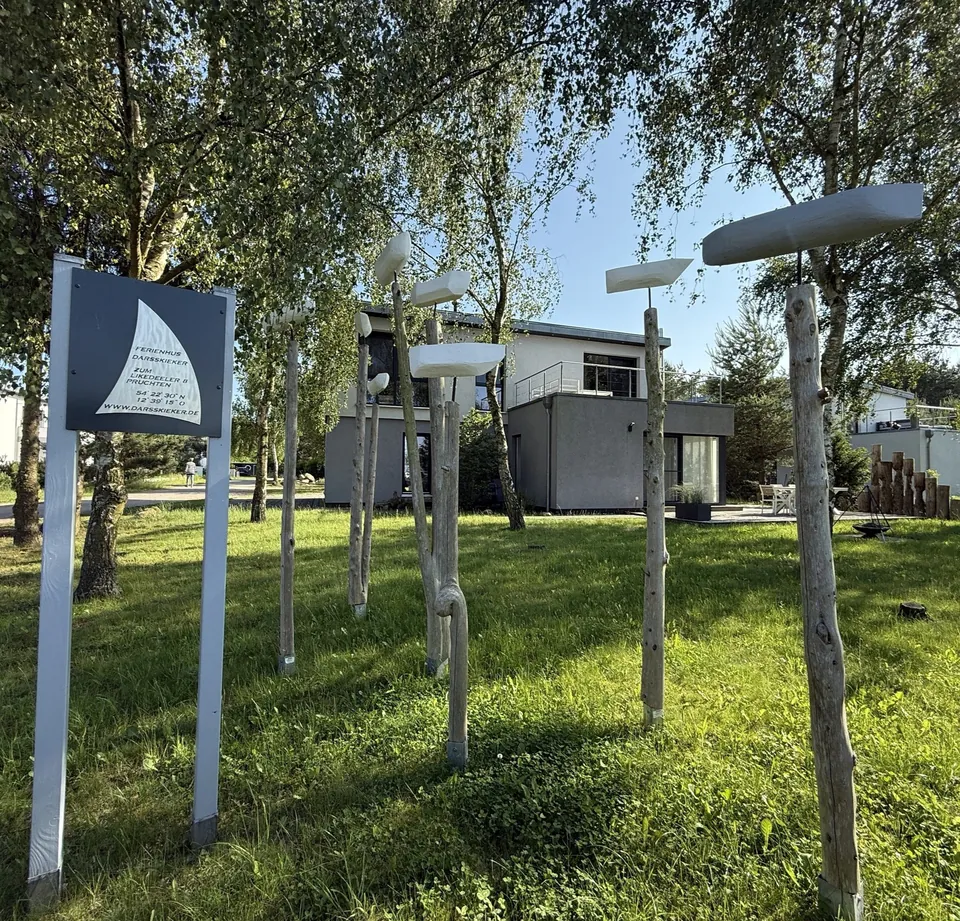 Garten mit Holzstelen und einem Schild zwischen jungen Birken