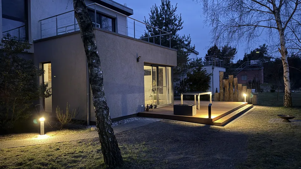 Das Ferienhaus am Abend mit beleuchteter Terrasse und Wegeleuchten