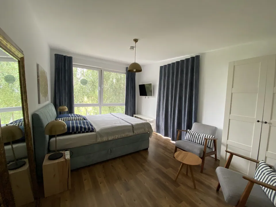 Schlafzimmer mit Boxspringbett und großen Fenstern zum Garten