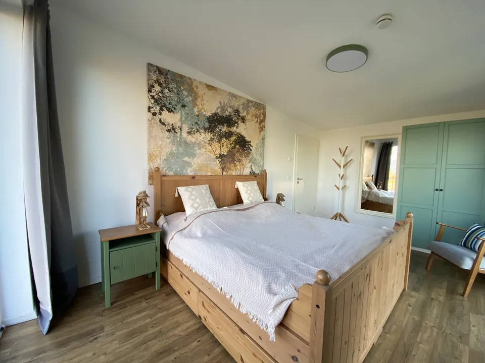 Schlafzimmer mit Holzbett, Wandbild und Kleiderschrank