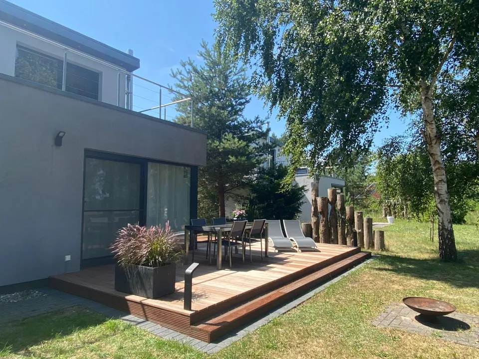 Terrasse mit Sitzgruppe und Feuerschale, daneben Birken und Kiefern