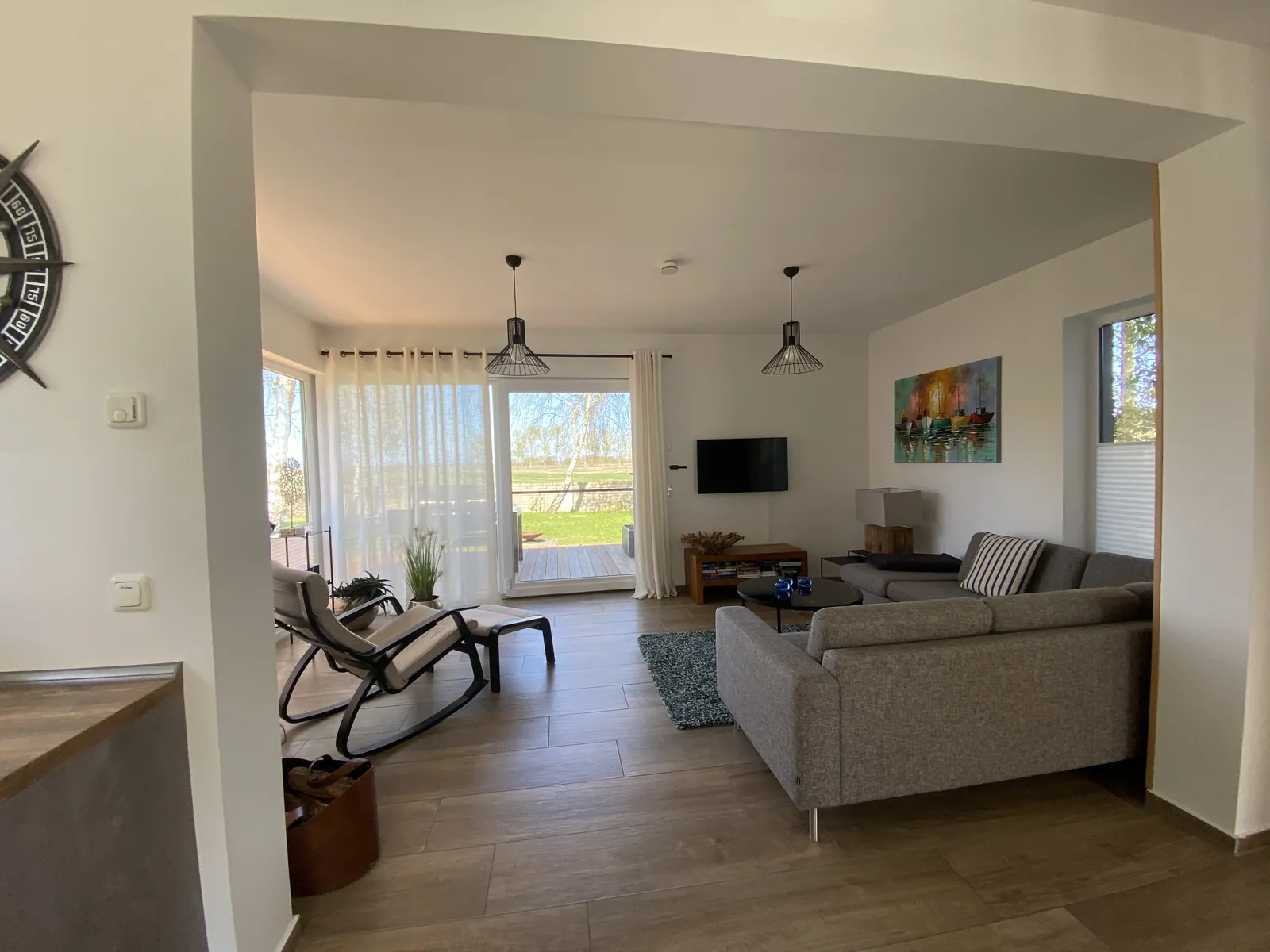 Offenes Wohnzimmer mit Sofa und Blick durch die bodentiefen Fenster nach draußen